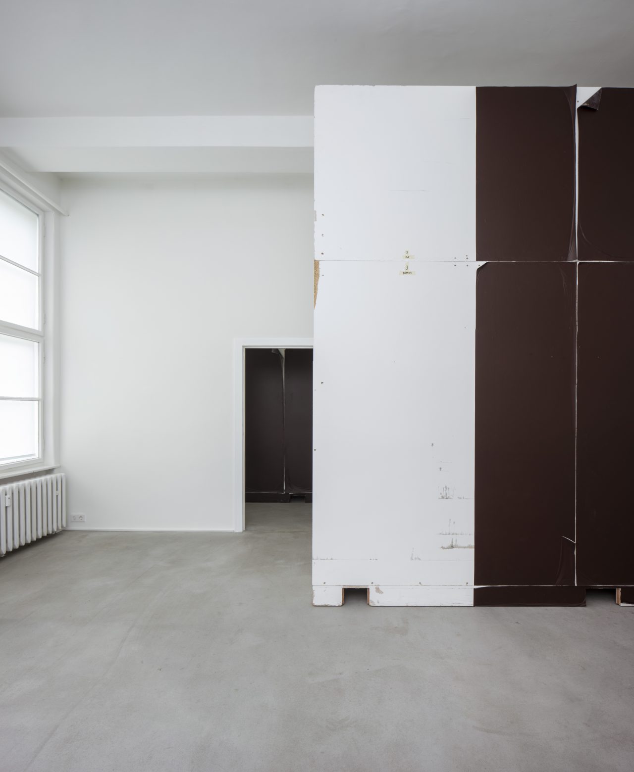 Foreground: Christopher Williams: Wall designed by Dirk Ufermann, Head Technician, Bonner Kunstverein, Bonn. Constructed by Objekt Design Persighetti Ltd. for the exhibition Open Letter: The Family Drama Refunctioned? (From the Point of View of Production), 17 March - 20 May, 2017, David Zwirner, London after drawings by Pasztori Simons Architects, Berlin with AAvery Dennison 507 EF Event Film Matt vinyl installed by Imga Imaging Ltd. Kent, UK (4/6) 2017 Plywood, metal, wood, and adhesive vinyl 350 x 350 x 57 cm Wall constructed by Objekt Design Persighetti Ltd, Leichlingen, Germany Vinyl installed by Igma Imaging Ltd., Kent, UK, 2017 Plywood, metal, wood, and adhesive vinyl 137 7/8 x 137 7/8 x 22 1/2 inches 350 x 350 x 57 cm WILCH0547, Background: Wall designed by Dirk Ufermann, Head Technician, Bonner Kunstverein, Bonn. Constructed by Objekt Design Persighetti Ltd. for the exhibition Open Letter: The Family Drama Refunctioned? (From the Point of View of Production), 17 March - 20 May, 2017, David Zwirner, London after drawings by Pasztori Simons Architects, Berlin with Avery Dennison 507 EF Event Film Matt vinyl installed by Imga Imaging Ltd. Kent, UK (2/6) 2017 Plywood, metal, wood, and adhesive vinyl 350 x 350 x 57 cm Wall constructed by Objekt Design Persighetti Ltd, Leichlingen, Germany Vinyl installed by Igma Imaging Ltd., Kent, UK, 2017 Plywood, metal, wood, and adhesive vinyl 137 7/8 x 137 7/8 x 22 1/2 inches 350 x 350 x 57 cm WILCH0545